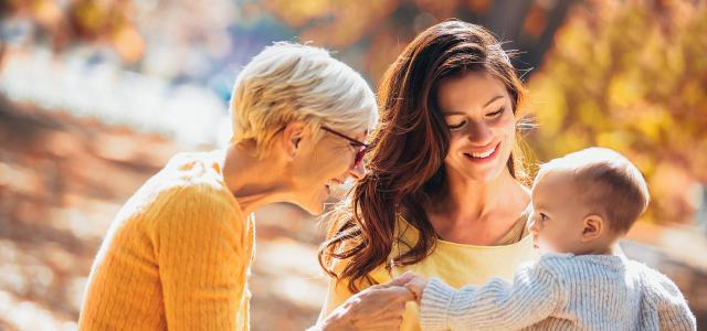 Grandmother and Mother Smiling at Baby in Autumn Park